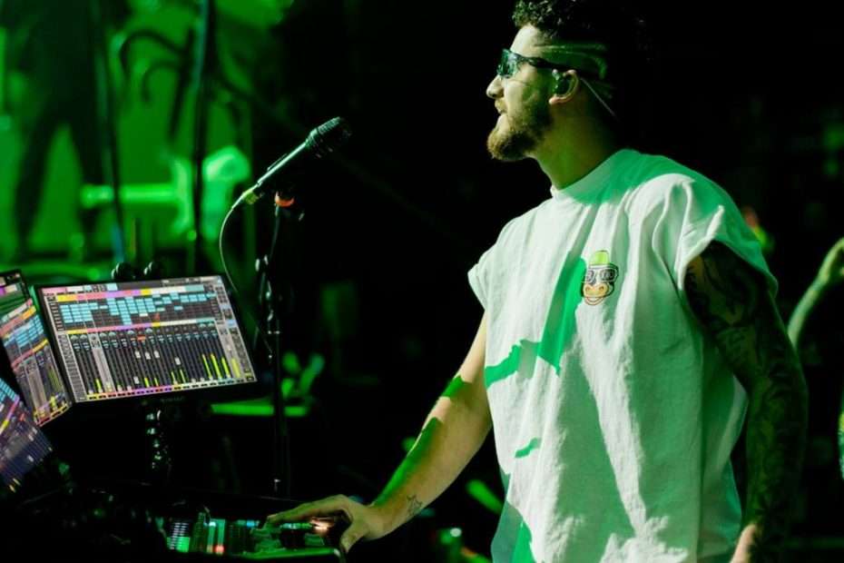 Feid monitor engineer Carlos Dickson adjusts Lectrosonics wireless rig on stage.