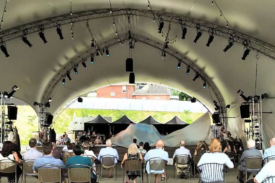 Stratford Festival audience seated under a large tent, enjoying outdoor live theatre.