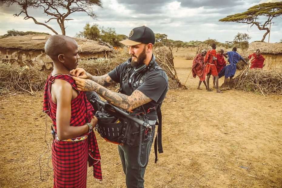 Filmmaker adjusts microphone on Maasai warrior in Kenya, using Lectrosonics gear.