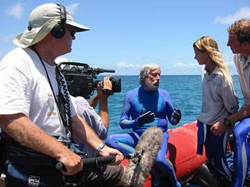 Filming a documentary about the Voyage to Kure with a man in a blue wetsuit