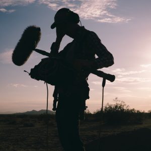 Desert-Heat4 Will Harrell silhouetted with boom mic and recorder in desert landscape