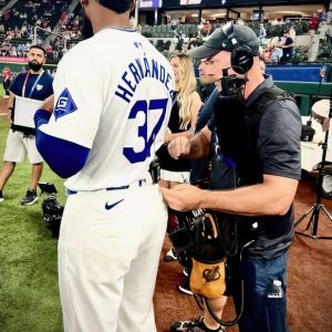 Hernandez #37 adjusts mic pack with sound technician during baseball game