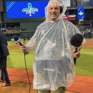 Greg Murphy in poncho with microphones at Chase Field, ready for broadcast.
