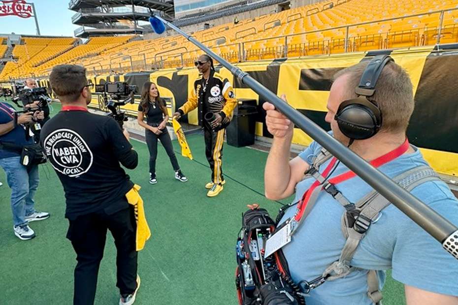 Snoop Dogg on NFL field with broadcast crew, including Henri Rapp.