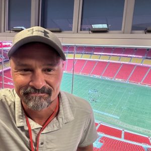 Paul Hunt in stadium suite with Kansas City Chiefs field below, using Lectrosonics.
