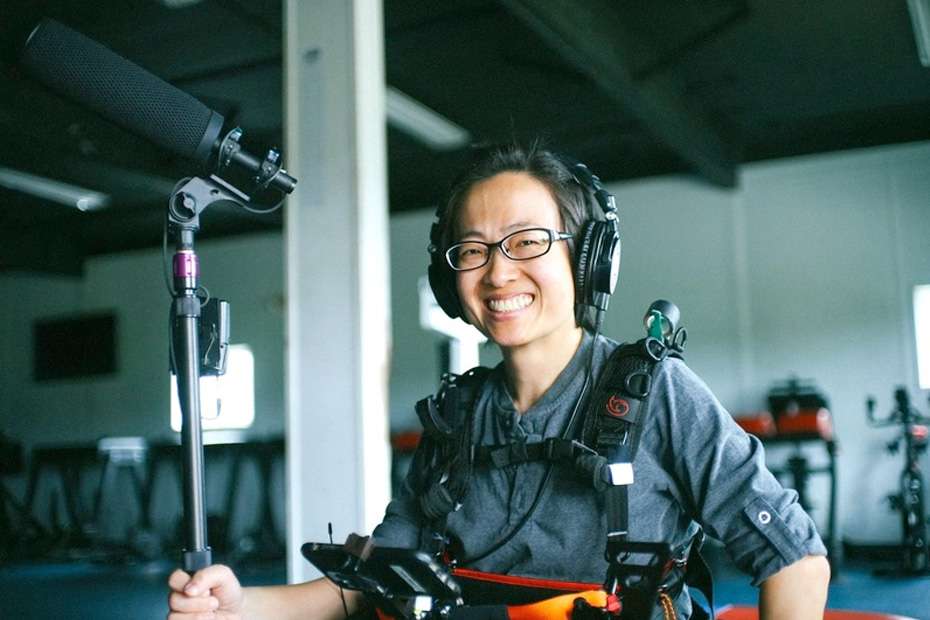 Shuling Yong smiles with a boom mic and Lectrosonics wireless gear, capturing authentic stories.