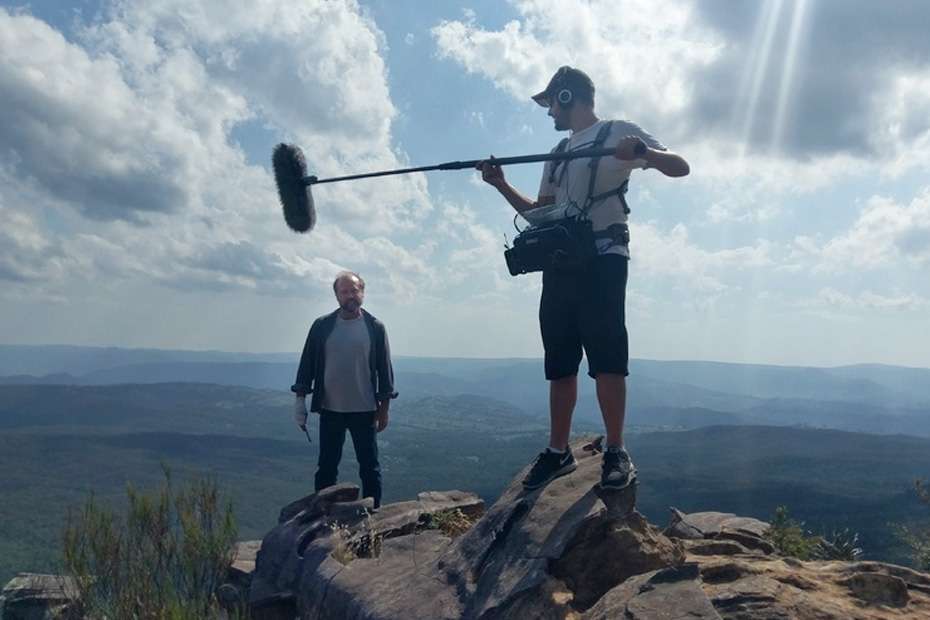 Sound recordist booms for Joseph Dutaillis on a mountaintop.