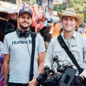Joseph Dutaillis and colleague with film gear in a bustling market